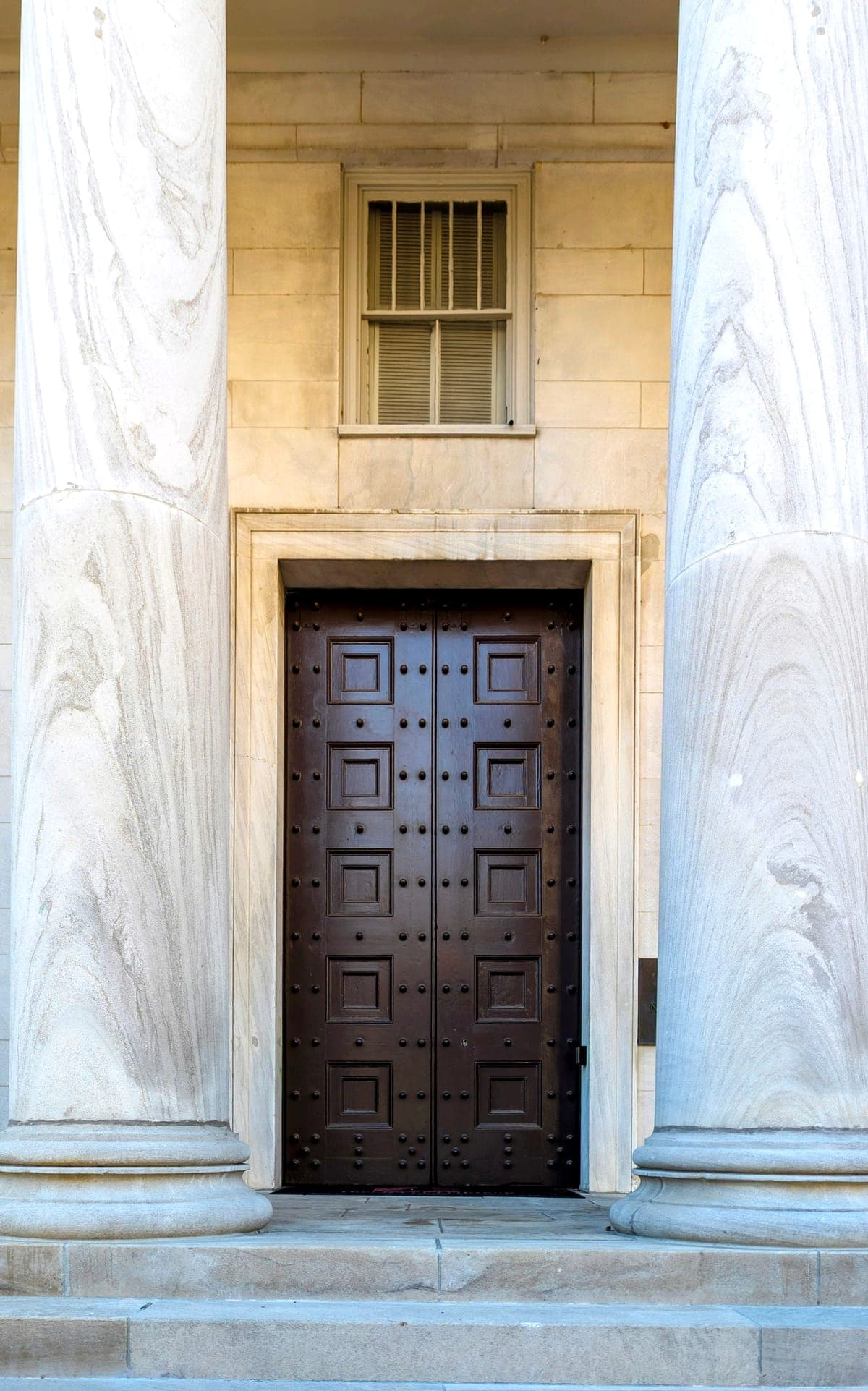 Columnas de piedra y puerta de acceso de un edificio institucional.
