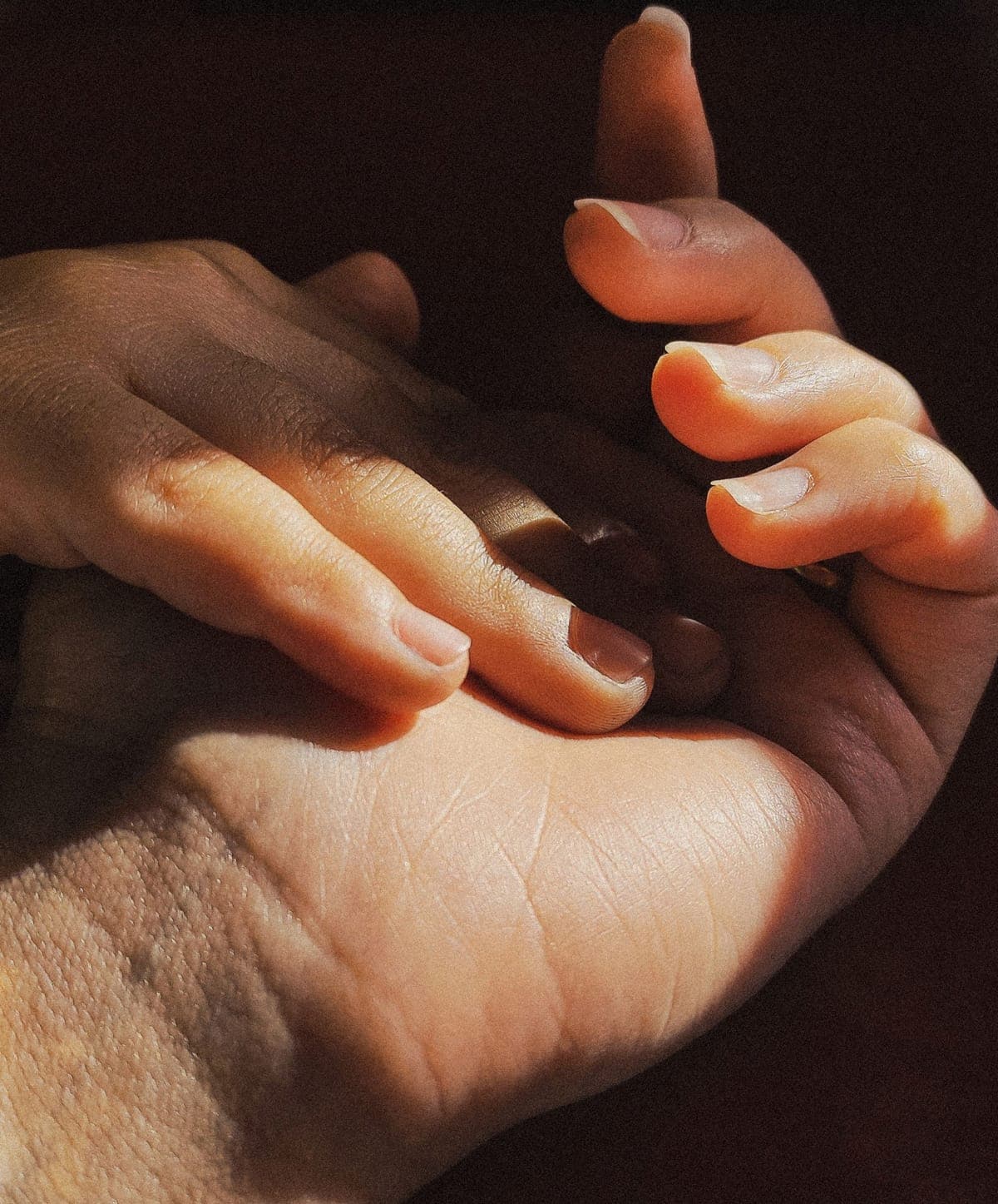 Mano de una persona adulta sosteniendo con cuidado la mano de un niño.